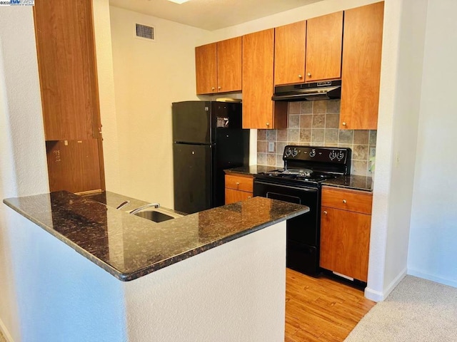 kitchen featuring backsplash, dark stone countertops, kitchen peninsula, and black appliances