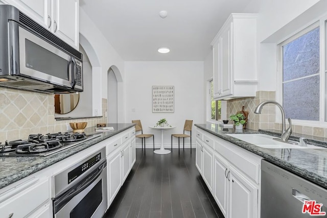 kitchen with light stone countertops, white cabinetry, appliances with stainless steel finishes, and sink