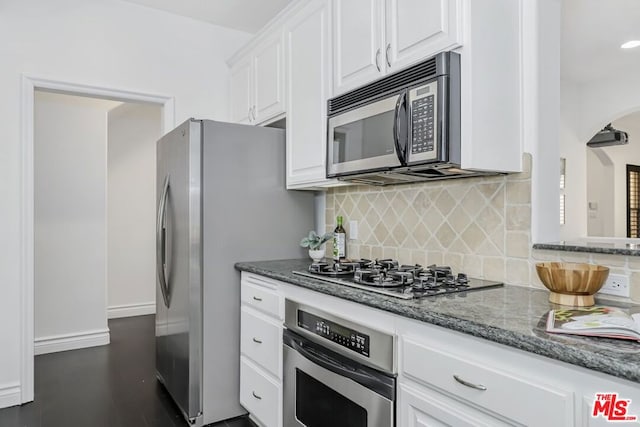 kitchen with dark stone counters, dark hardwood / wood-style flooring, stainless steel appliances, decorative backsplash, and white cabinets