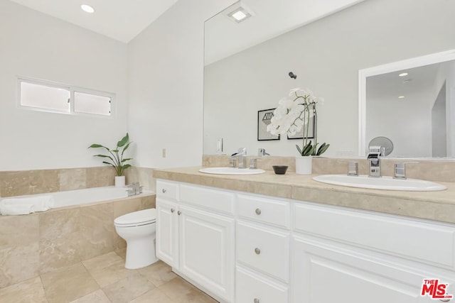 bathroom with vanity, tiled tub, and toilet