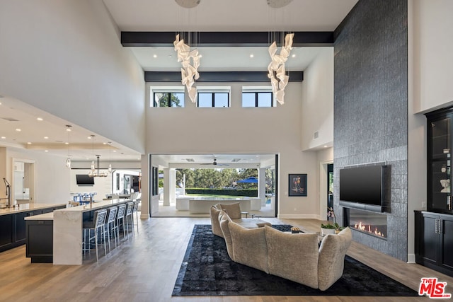 living room with a towering ceiling, a fireplace, light hardwood / wood-style floors, and a chandelier