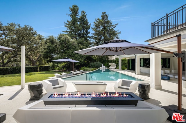 view of pool featuring a patio area, a fire pit, and a lawn