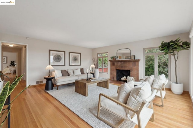 living room featuring a brick fireplace and light hardwood / wood-style floors