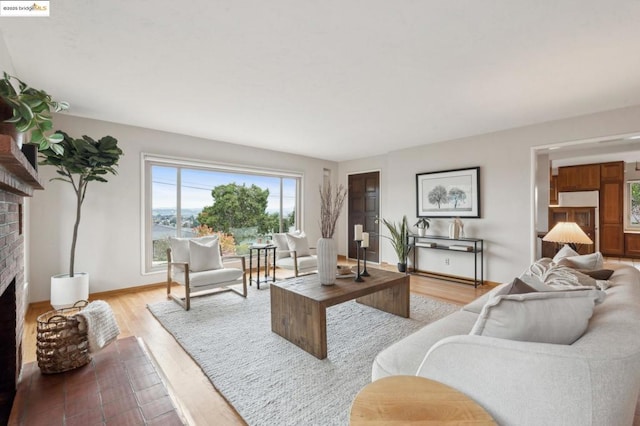 living room featuring a brick fireplace and light wood-type flooring