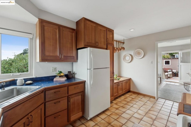 kitchen featuring sink, tile countertops, light tile patterned flooring, and white refrigerator