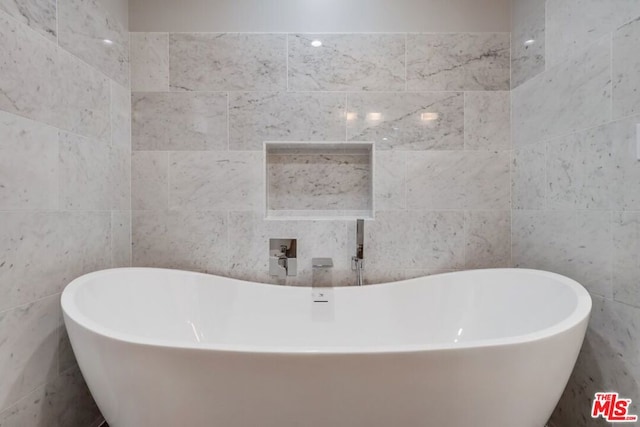 bathroom with tile walls and a tub