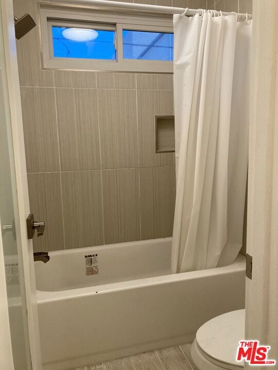 bathroom featuring toilet and shower / bath combo with shower curtain