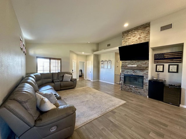 living room featuring lofted ceiling, hardwood / wood-style floors, and a fireplace