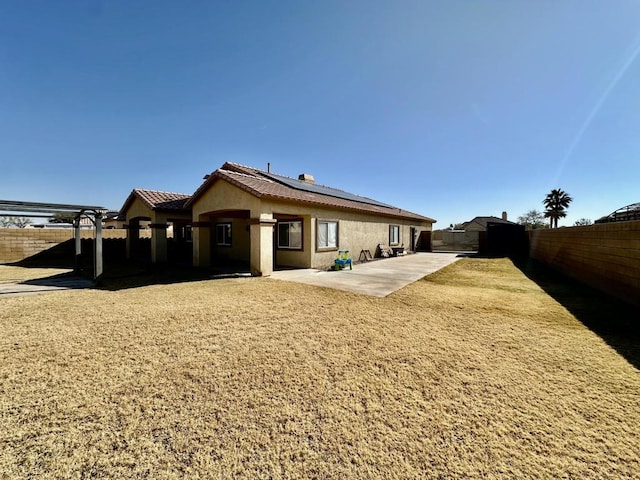 back of property with a patio and solar panels