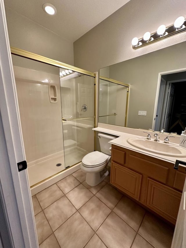 bathroom featuring tile patterned floors, toilet, a shower with shower door, and vanity