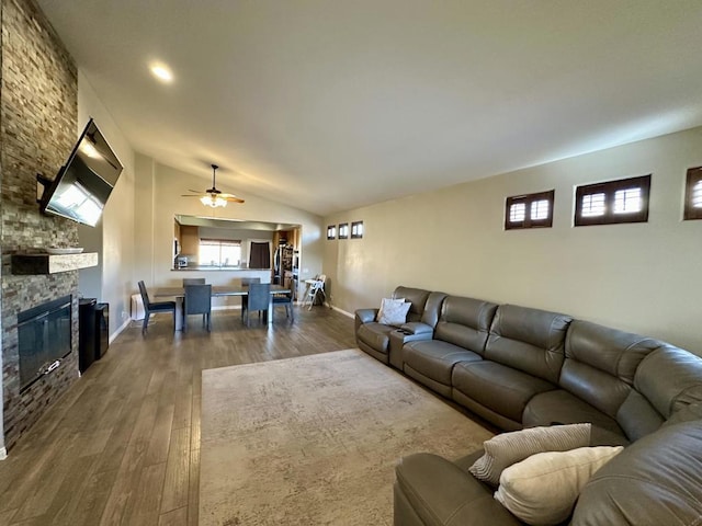 living room with dark hardwood / wood-style floors, lofted ceiling, a stone fireplace, and plenty of natural light