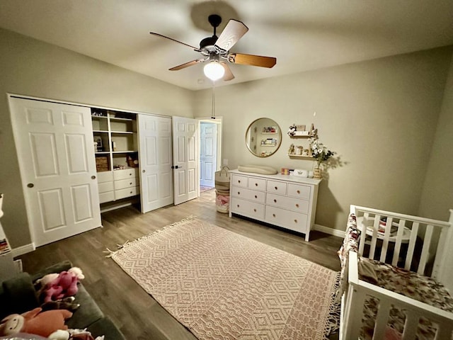 bedroom featuring hardwood / wood-style floors, a nursery area, a closet, and ceiling fan