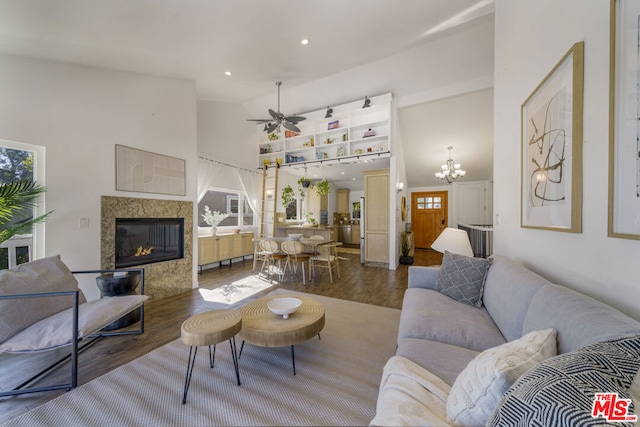 living room with ceiling fan with notable chandelier, high vaulted ceiling, a premium fireplace, and hardwood / wood-style floors