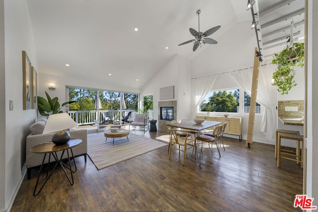 living room featuring dark wood-type flooring, high vaulted ceiling, a healthy amount of sunlight, and a multi sided fireplace