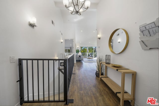 hallway with a towering ceiling, a chandelier, and dark hardwood / wood-style flooring