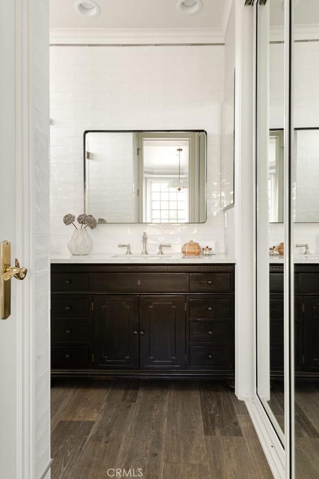 bathroom with crown molding, hardwood / wood-style flooring, vanity, tasteful backsplash, and walk in shower