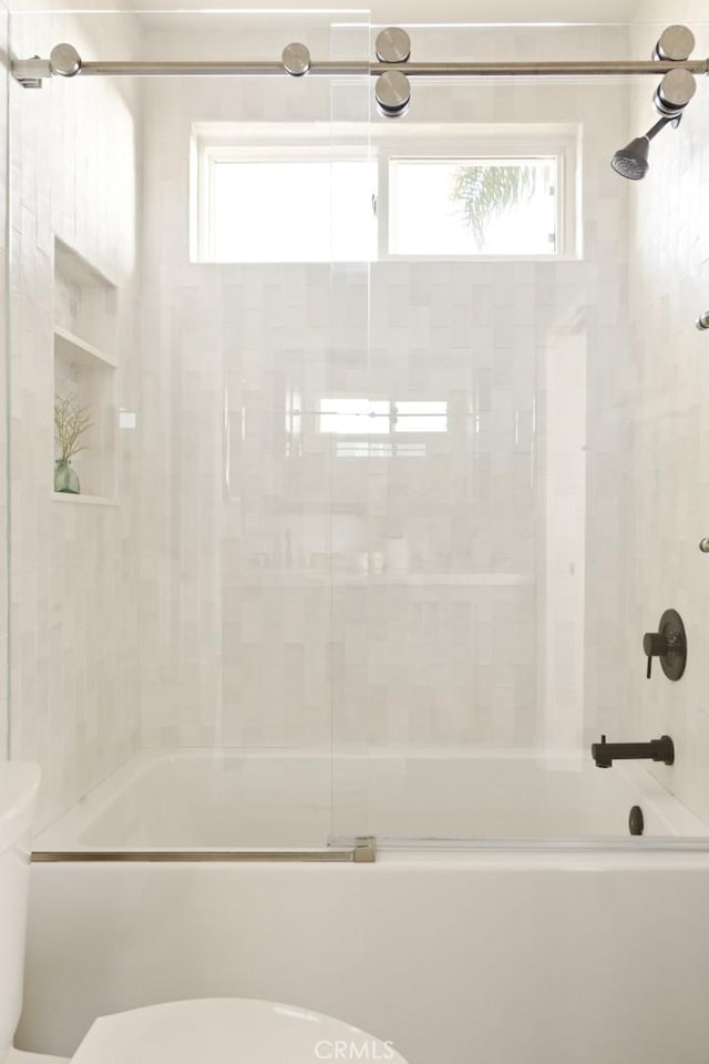 bathroom featuring bath / shower combo with glass door, a wealth of natural light, and toilet