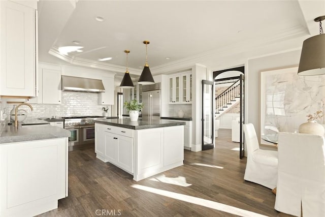 kitchen featuring white cabinetry, sink, hanging light fixtures, a center island, and wall chimney exhaust hood