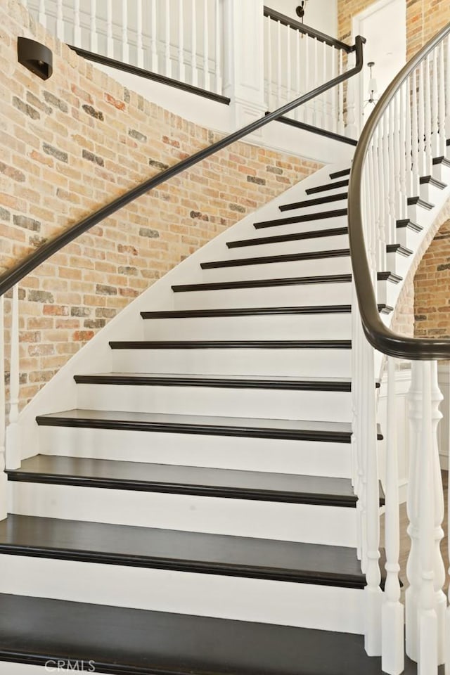 stairway with brick wall and a high ceiling