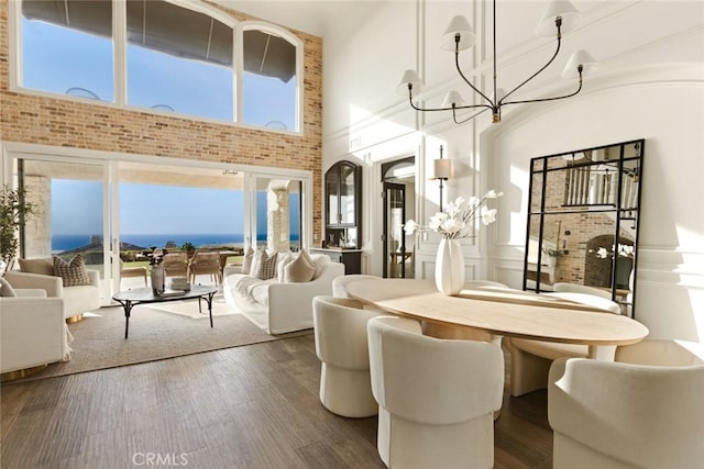 dining space featuring an inviting chandelier, a towering ceiling, and dark hardwood / wood-style flooring