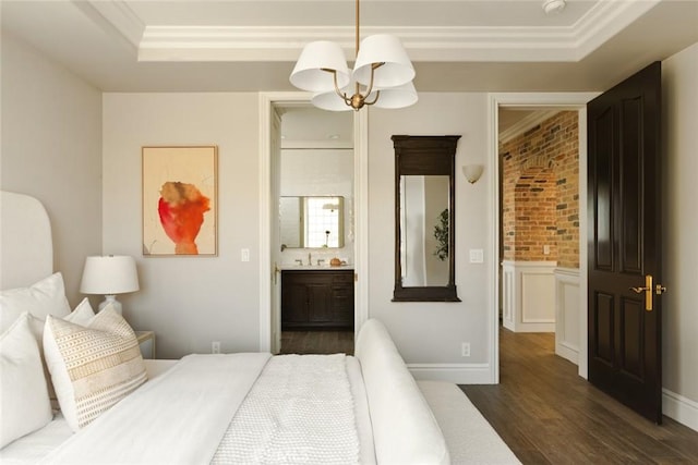 bedroom with dark wood-type flooring, crown molding, ensuite bath, a chandelier, and a raised ceiling