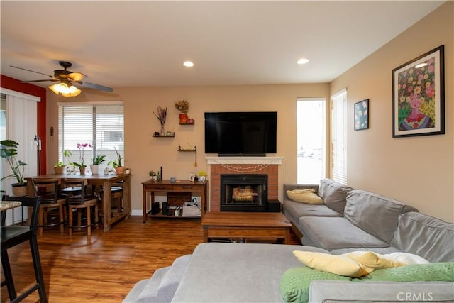 living room featuring hardwood / wood-style floors, a brick fireplace, and ceiling fan