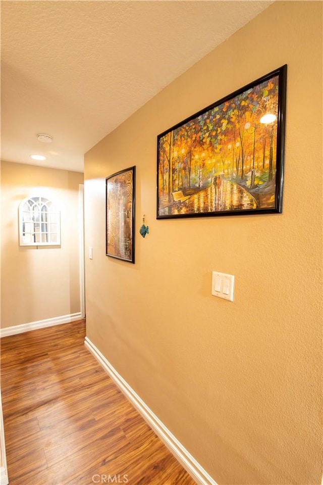 hall with hardwood / wood-style flooring and a textured ceiling