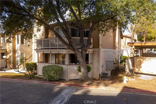 view of front of house featuring a balcony and central air condition unit