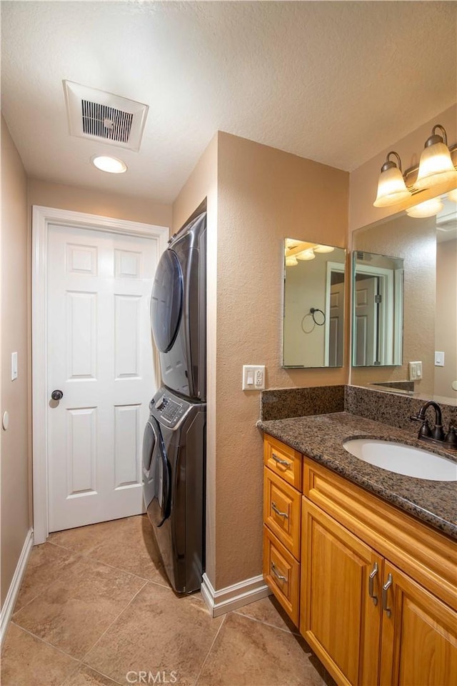 bathroom with tile patterned floors, stacked washer / drying machine, and vanity