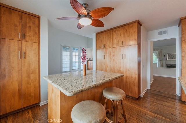 kitchen with light stone counters, dark wood-style flooring, visible vents, and baseboards