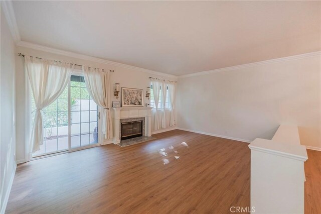 unfurnished living room with ornamental molding, a premium fireplace, wood finished floors, and baseboards