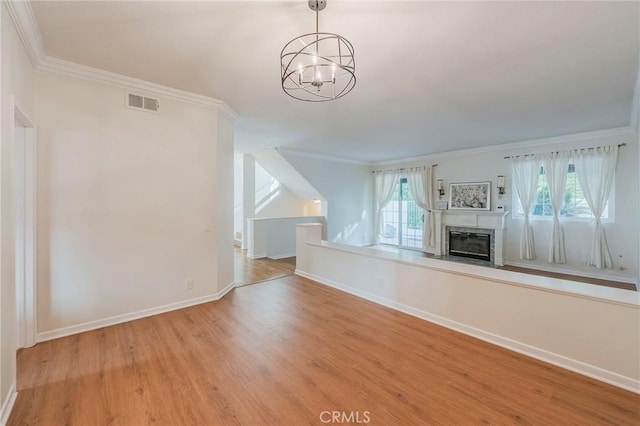 unfurnished living room featuring visible vents, ornamental molding, a high end fireplace, wood finished floors, and baseboards