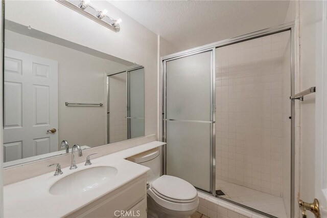 full bath with toilet, a stall shower, a textured ceiling, and vanity