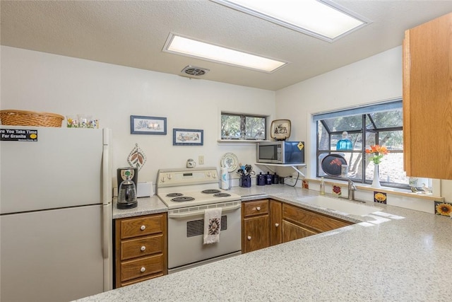 kitchen featuring sink, white appliances, light stone countertops, and a textured ceiling