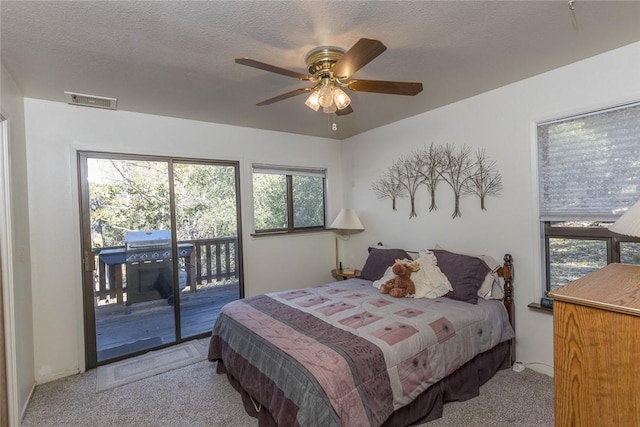 carpeted bedroom with ceiling fan, access to exterior, and a textured ceiling