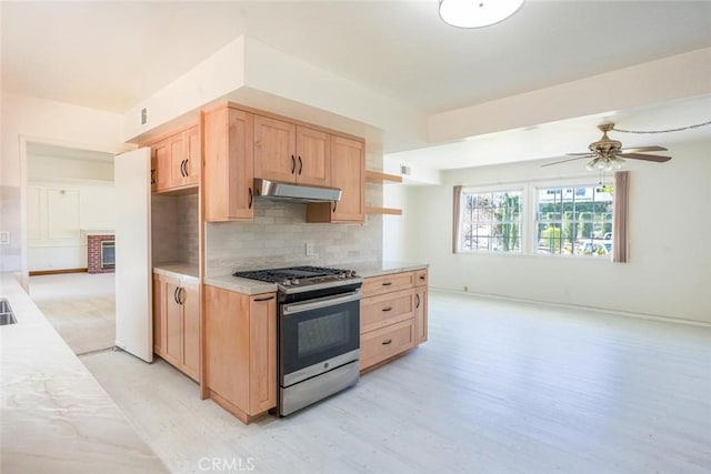 kitchen with gas range, tasteful backsplash, light brown cabinets, ceiling fan, and light hardwood / wood-style floors