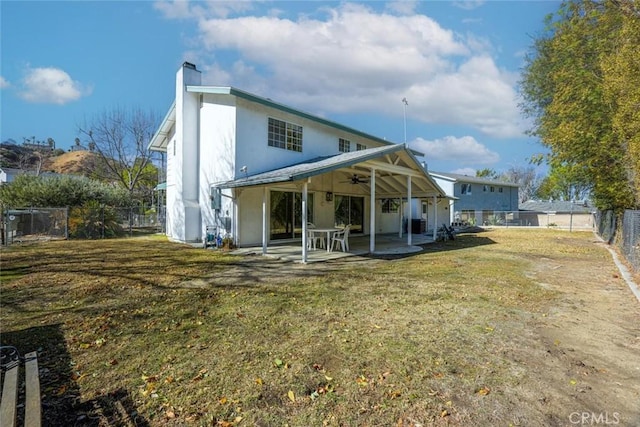 rear view of house featuring ceiling fan, a yard, and a patio