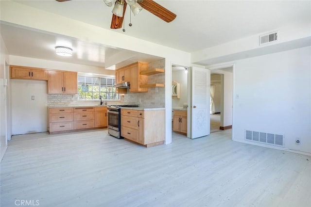 kitchen featuring backsplash, ceiling fan, light brown cabinets, stainless steel gas range, and light hardwood / wood-style flooring