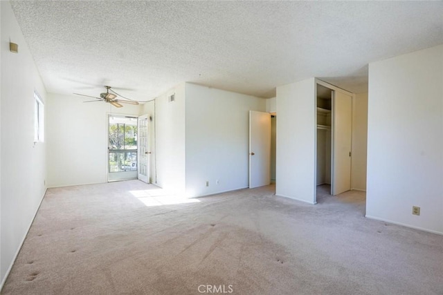 unfurnished room featuring ceiling fan, light colored carpet, and a textured ceiling