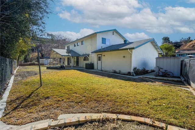 back of house featuring central AC, a patio, a storage unit, and a lawn