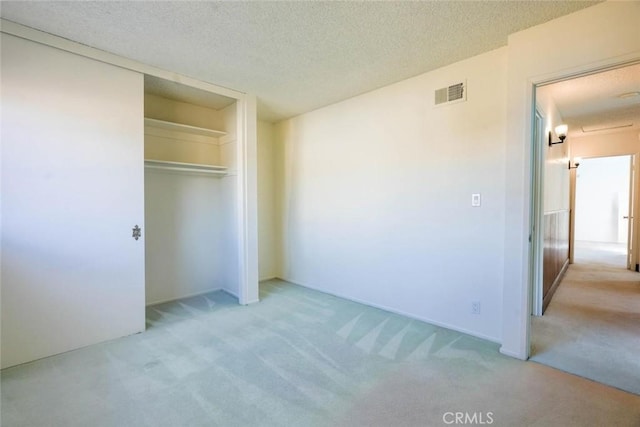 unfurnished bedroom featuring light colored carpet, a closet, and a textured ceiling