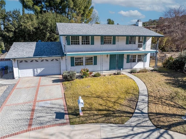 view of front of property featuring a garage, a front yard, and a porch