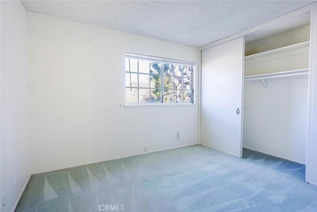 unfurnished bedroom with carpet floors, a closet, and a textured ceiling