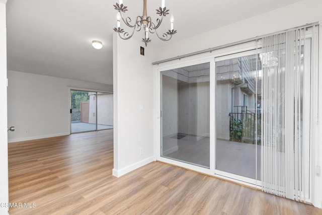 empty room featuring an inviting chandelier and hardwood / wood-style floors