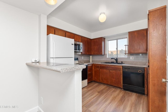 kitchen featuring sink, backsplash, kitchen peninsula, white appliances, and light hardwood / wood-style flooring