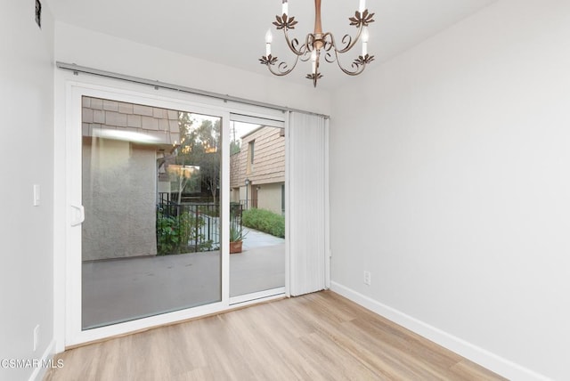 unfurnished room with an inviting chandelier and light hardwood / wood-style floors