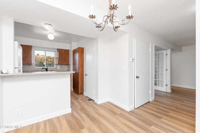 kitchen with white fridge, pendant lighting, light wood-type flooring, and decorative backsplash