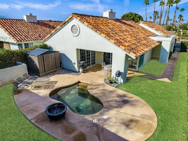 rear view of house with a storage shed, a patio area, and a lawn