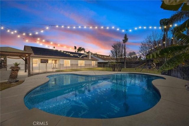 pool at dusk featuring a patio