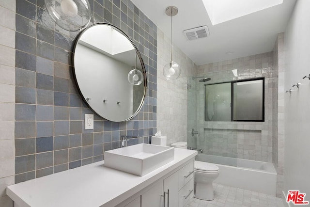 full bathroom featuring tiled shower / bath, toilet, tile walls, and a skylight